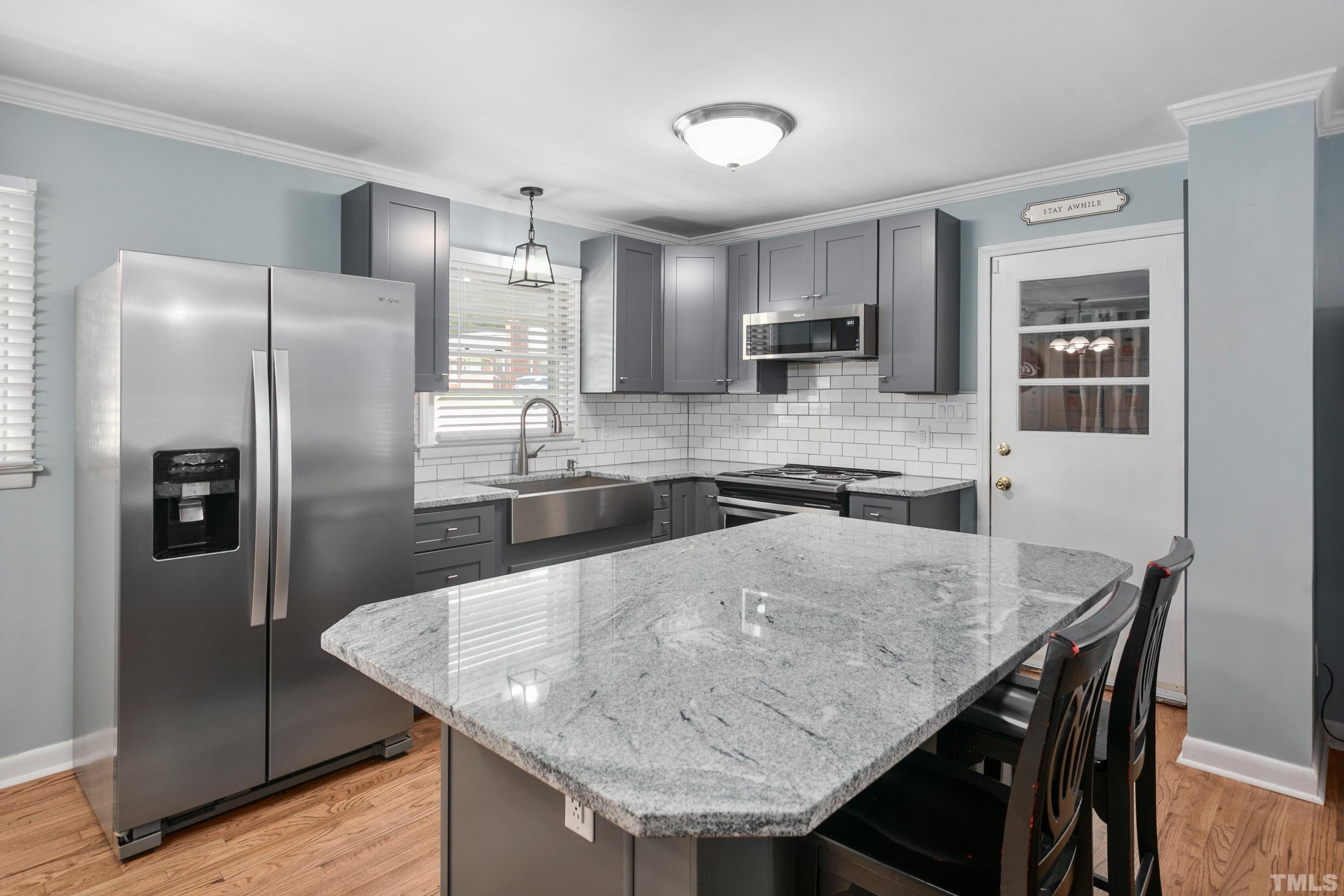 3702 Randell Road Garner, NC 27529 - Photo 8 of 24 a kitchen with stainless steel appliances granite countertop a table chairs refrigerator and microwave