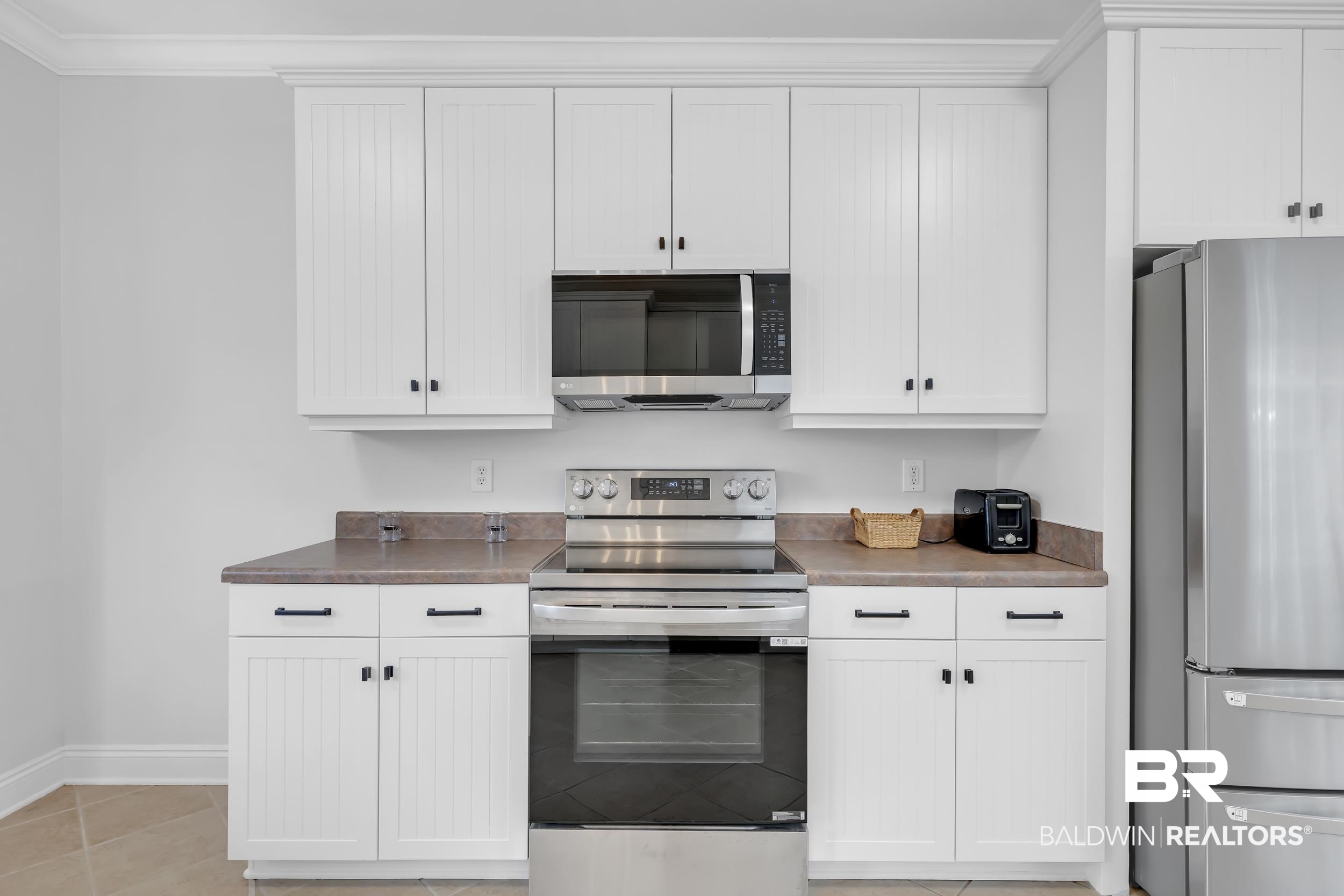 105 Mark Twain Loop Foley, AL 36535 - Photo 6 of 43 Kitchen with stainless steel appliances, white cabinetry, ornamental molding, dark countertops, and light tile patterned flooring