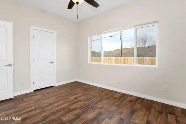 a view of an empty room with wooden floor and a window