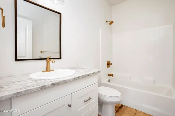a bathroom with a granite countertop toilet sink and mirror