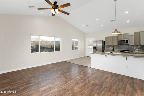 a kitchen with stainless steel appliances kitchen island granite countertop a stove top oven a sink with wooden floors and cabinets