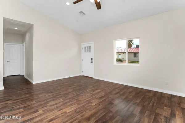 an empty room with wooden floor chandelier fan and windows