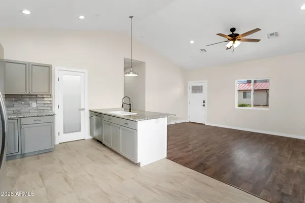 a large kitchen with a large counter top a sink stainless steel appliances and cabinets