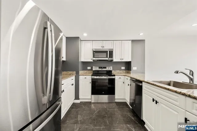 a kitchen with stainless steel appliances granite countertop a refrigerator sink and stove