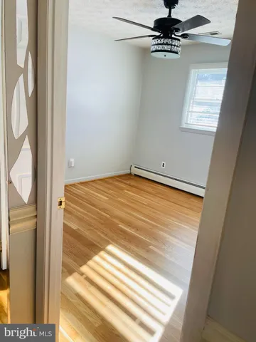 a view of an empty room with wooden floor and a bathroom