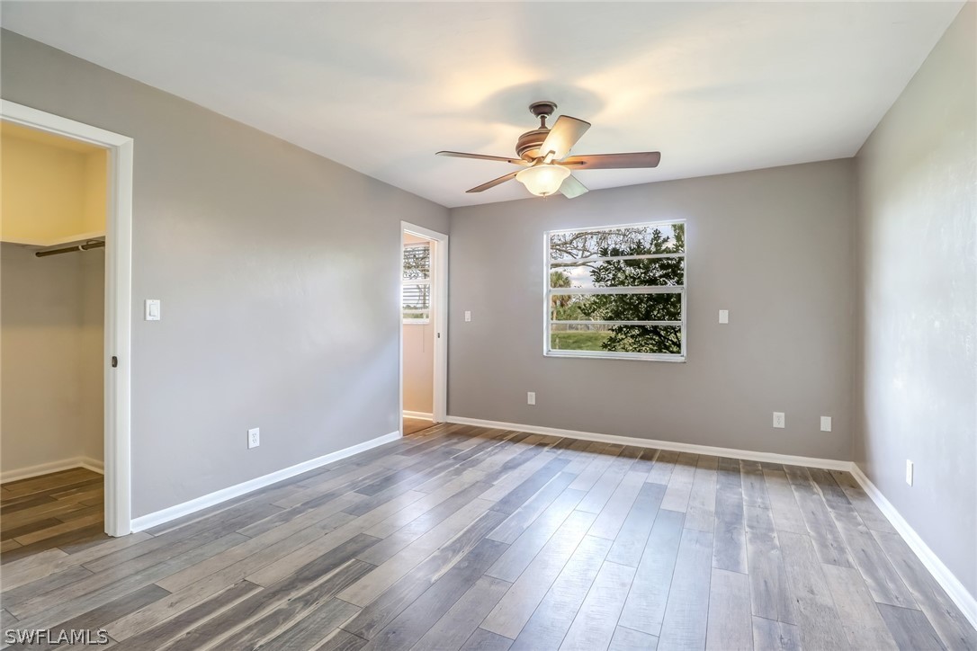 5381 Jackson Road Fort Myers, FL 33905 - Photo 10 of 23 an empty room with wooden floor chandelier fan and windows