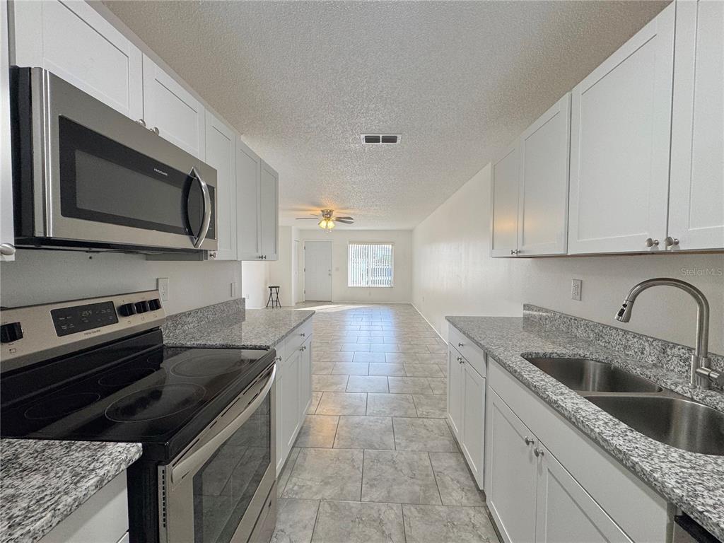 292 Winter Ridge Boulevard, Unit 292 Winter Haven, FL 33881 - Photo 9 of 37 a kitchen with granite countertop a sink and stove top oven