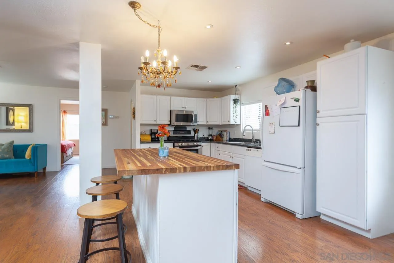 33475 Windmill Road Wildomar, CA 92595 - Photo 8 of 34 a kitchen with stainless steel appliances granite countertop a refrigerator a sink dishwasher a dining table and chairs with wooden floor