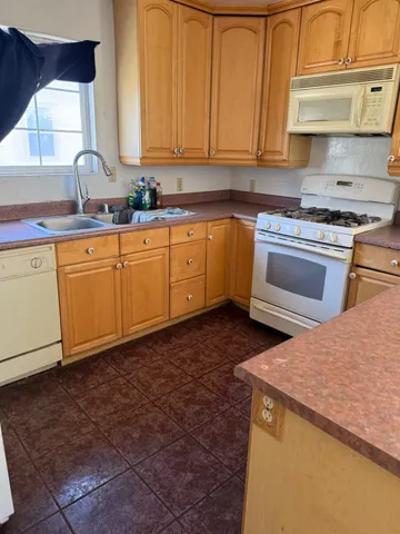 a kitchen with granite countertop a sink a stove and cabinets