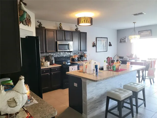 a kitchen with stainless steel appliances granite countertop a refrigerator a sink dishwasher a dining table and chairs with wooden floor