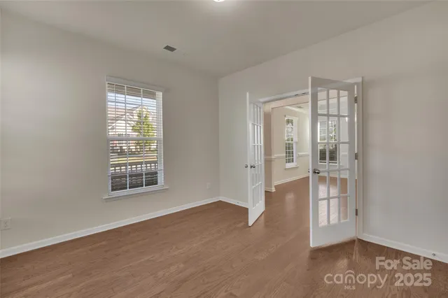an empty room with wooden floor and windows