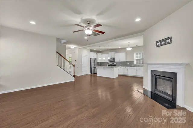 a view of an empty room wooden floor and a kitchen