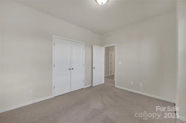 an empty room with chandelier fan and windows