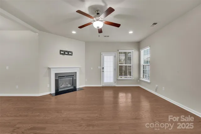 a view of an empty room with window and wooden floor