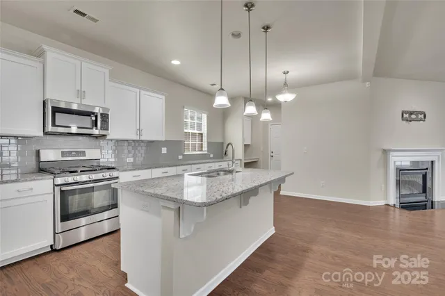a large kitchen with kitchen island a stove a sink a center island and wooden floor