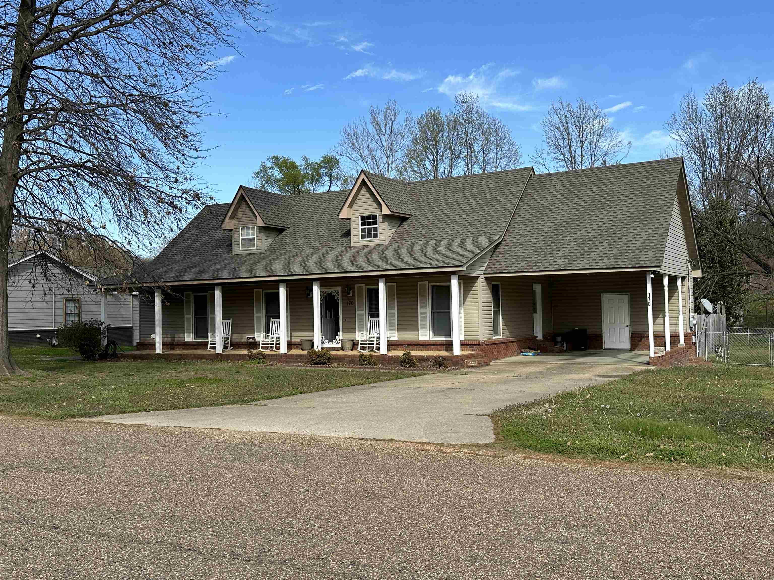 Farmhouse-style home featuring driveway, a front lawn, a shingled roof, and covered porch