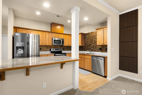 a kitchen with stainless steel appliances granite countertop a refrigerator a stove and a sink with wooden floor