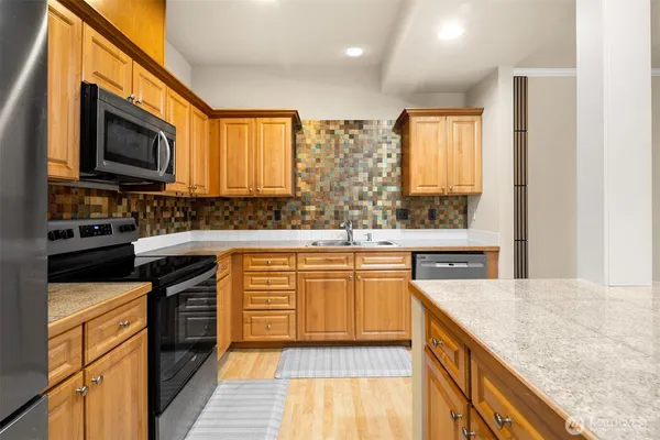 a kitchen with stainless steel appliances granite countertop a stove a sink and a microwave