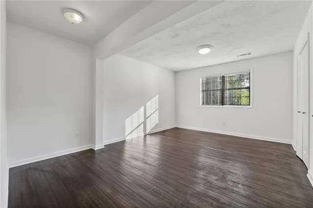 an empty room with wooden floor and windows