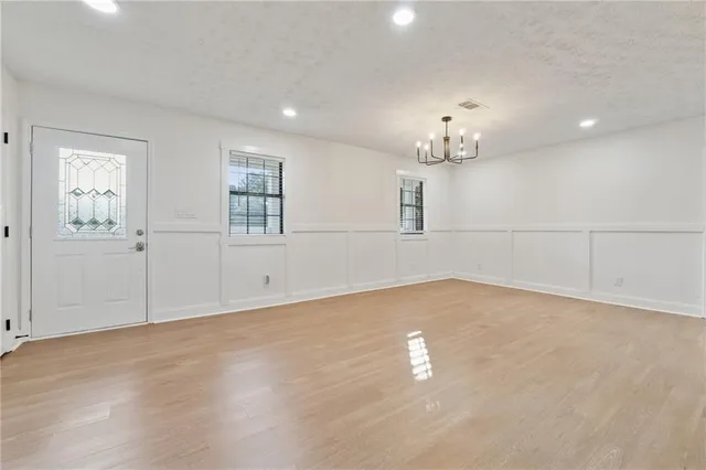 an empty room with chandelier fan and windows