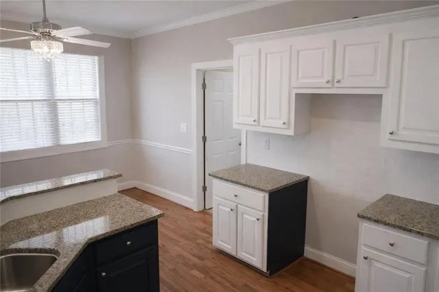a kitchen with granite countertop a sink a stove and cabinets