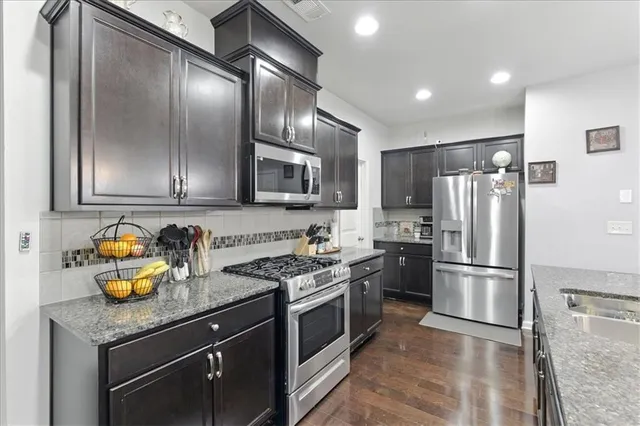 a kitchen with stainless steel appliances granite countertop a refrigerator a stove a sink and a microwave