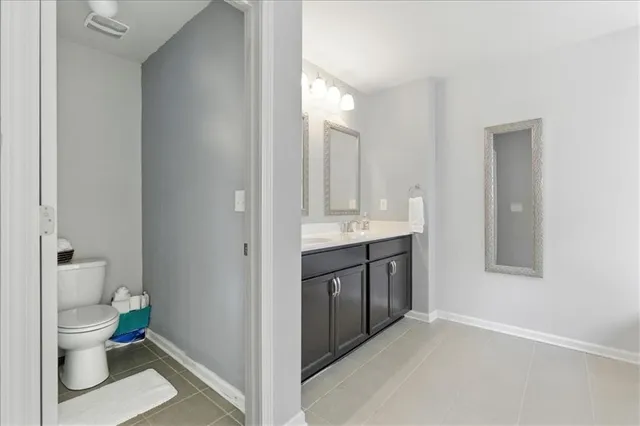 a bathroom with a granite countertop toilet a sink and a mirror