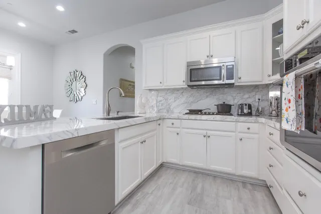 a kitchen with granite countertop a sink stainless steel appliances and cabinets