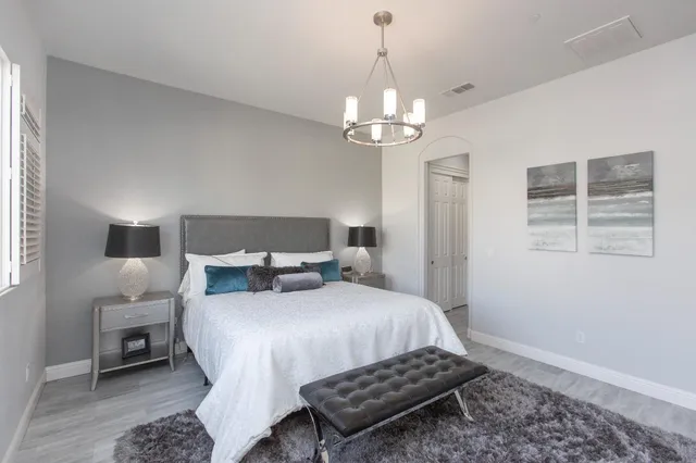 a bedroom with a bed chandelier and a window