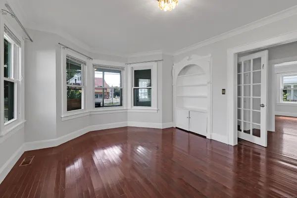 a view of an empty room with wooden floor and a window