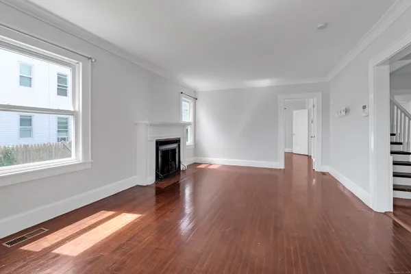 a view of an empty room with wooden floor and a window