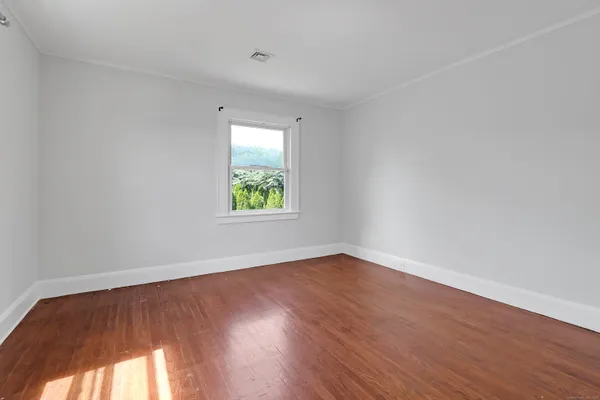 an empty room with wooden floor and window