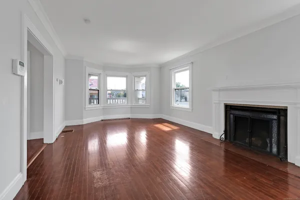 an empty room with wooden floor fireplace and windows