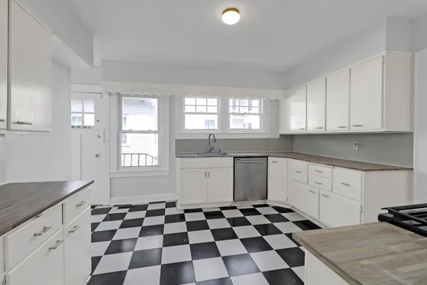 a kitchen with a checkered floor and white cabinets