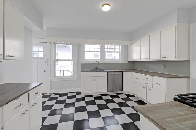 a kitchen with a checkered floor and white cabinets