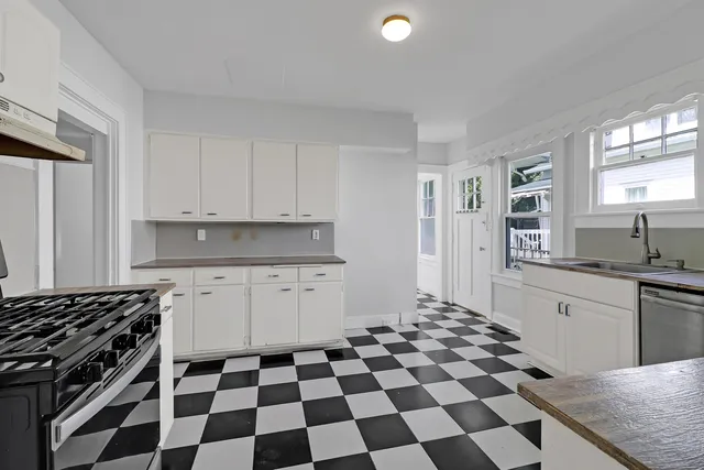 a kitchen with a checkered floor and white cabinets