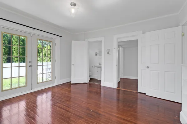 a view of an empty room with wooden floor and a window