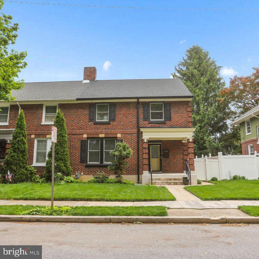 Charming brick duplex with lush greenery.
