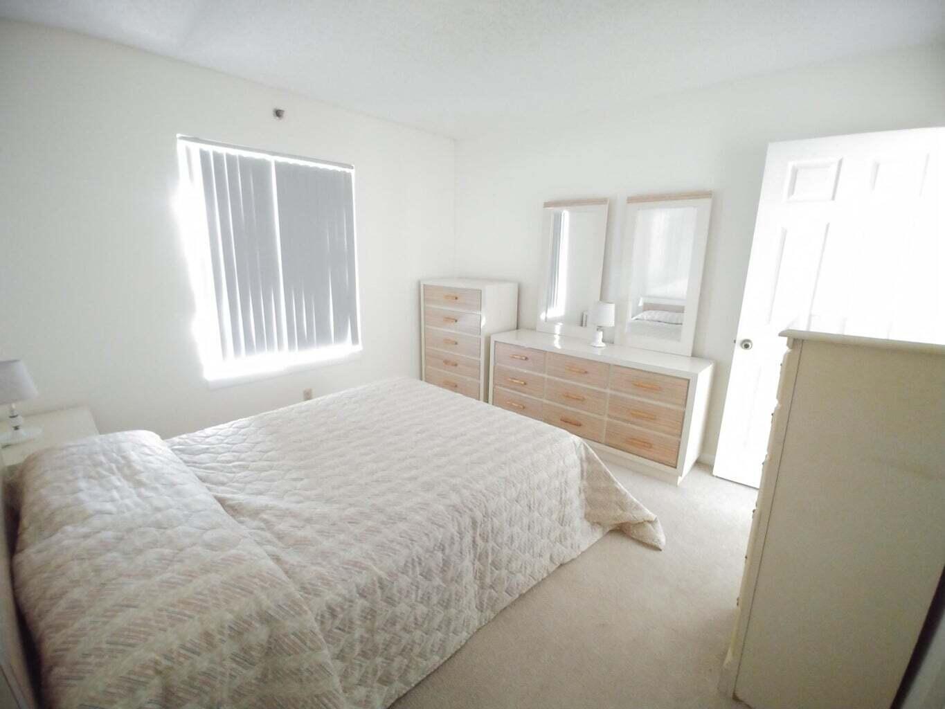 6258 Chasewood Drive, Unit E Jupiter, FL 33458 - Photo 8 of 15 a bedroom with a bed and a large mirror