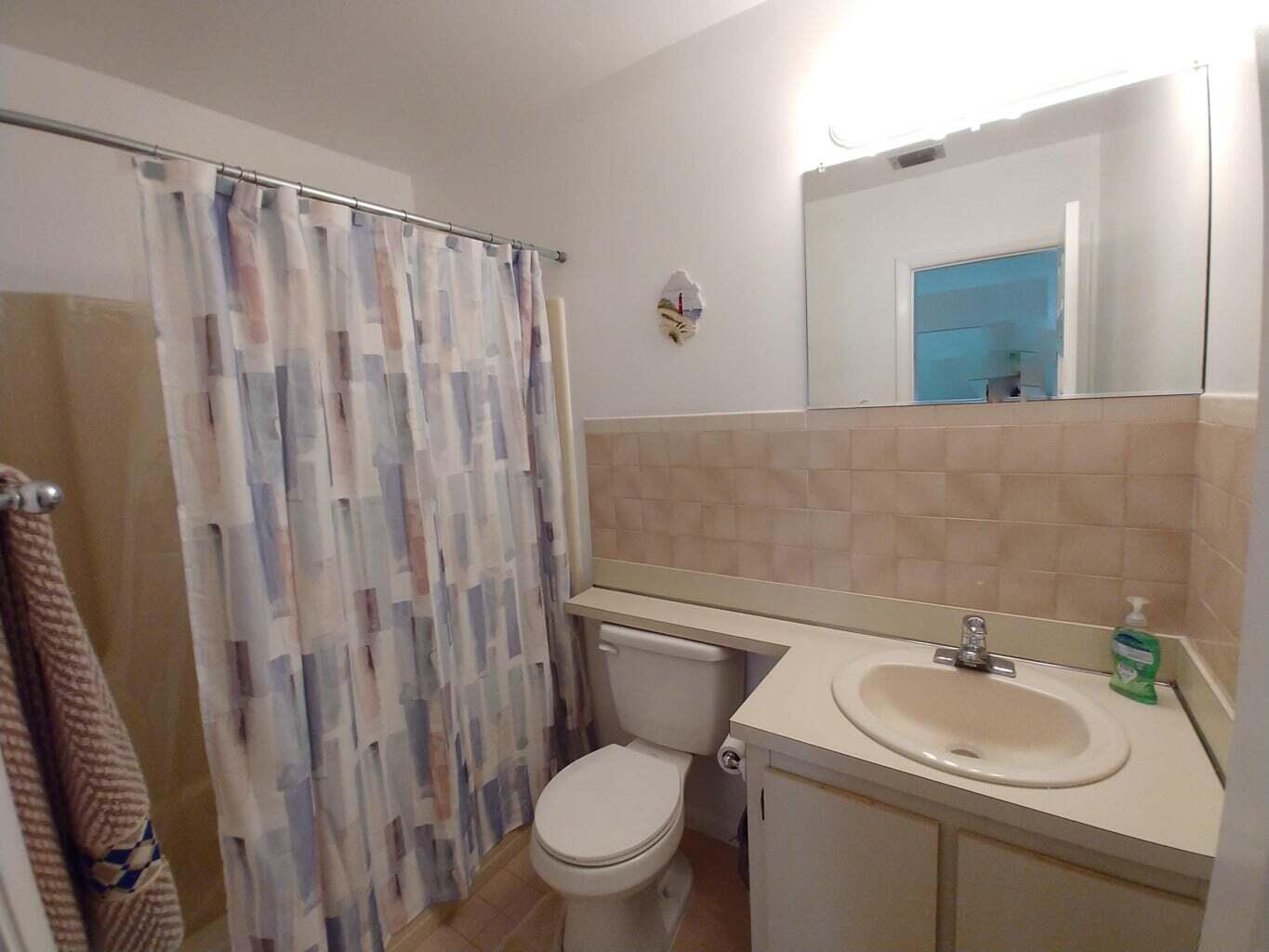 6258 Chasewood Drive, Unit E Jupiter, FL 33458 - Photo 9 of 15 a bathroom with a sink a toilet and a mirror