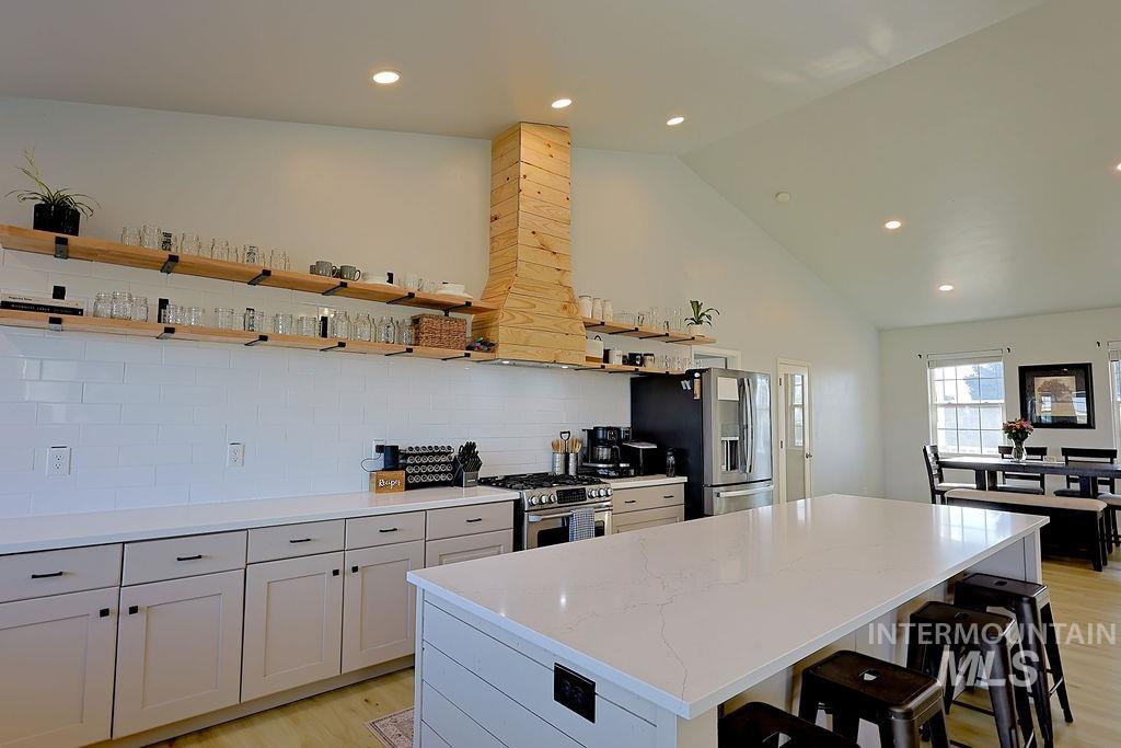 24 Harris Circle Shoshone, ID 83352 - Photo 11 of 39 Kitchen featuring light wood finished floors, a center island, vaulted ceiling, stainless steel appliances, and a kitchen breakfast bar