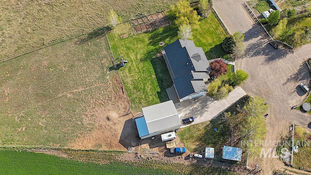 24 Harris Circle Shoshone, ID 83352 - Photo 37 of 39 Aerial perspective showcasing a single-family residence with a dark shingled roof, accompanied by a large detached metal-sided outbuilding