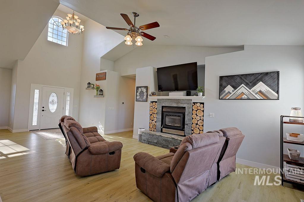 24 Harris Circle Shoshone, ID 83352 - Photo 7 of 39 Living room featuring a ceiling fan, plenty of natural light, light wood-style flooring, a stone fireplace, and lofted ceiling