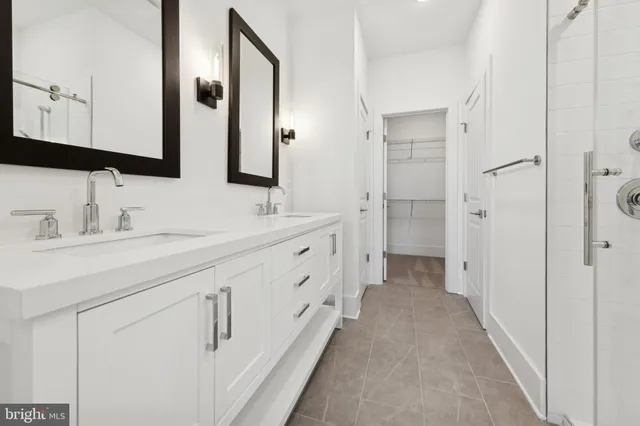 a bathroom with double vanity white cabinets and a mirror