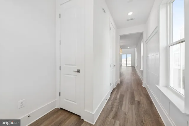 a view of a hallway with wooden floor and a bathroom