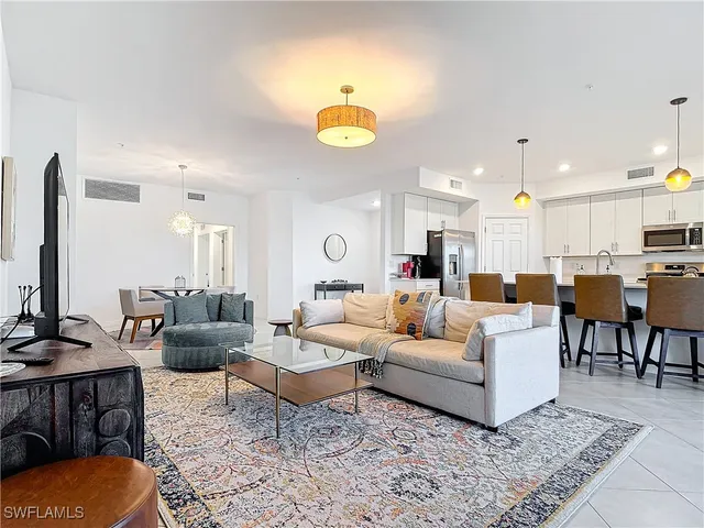 a living room with furniture kitchen view and a chandelier