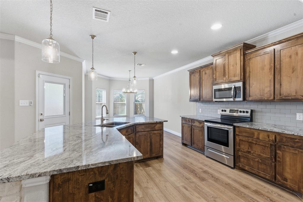 906 Chestnut Grove Drive Cleburne, TX 76033 - Photo 5 of 29 a kitchen with stainless steel appliances granite countertop a sink a stove and a wooden floors