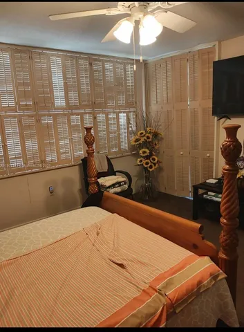 a bedroom with a bed a flat screen tv and a large window