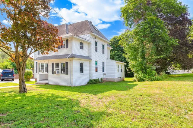 a view of a house with a yard and large trees