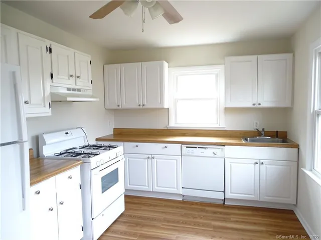 a kitchen with stainless steel appliances granite countertop a stove a sink and white cabinets